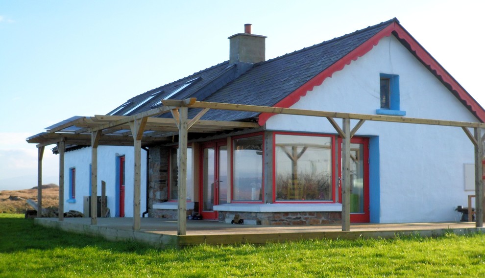 Exemple d'une petite façade de maison blanche bord de mer en pierre à un étage avec un toit à deux pans et un toit en tuile.