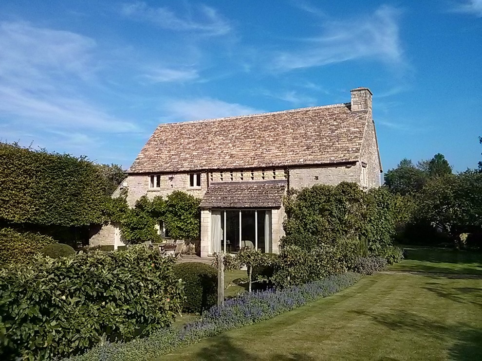 Réalisation d'une façade de maison champêtre en pierre avec un toit à deux pans.