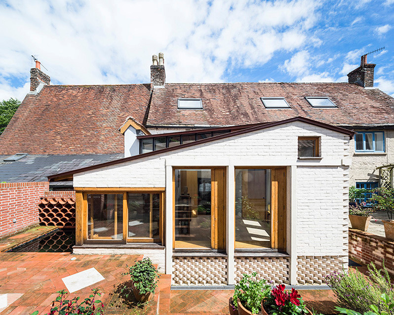 Immagine della facciata di una casa a schiera piccola bianca country a un piano con rivestimento in mattoni, tetto a capanna e copertura in metallo o lamiera