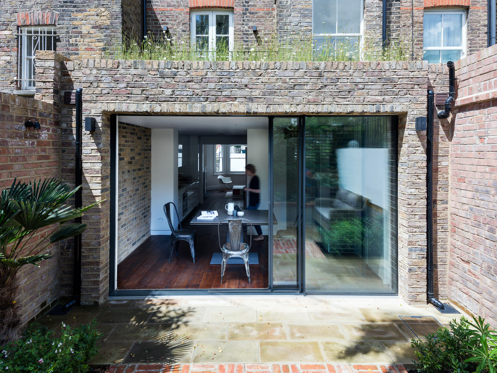 This is an example of a small contemporary two floor brick house exterior in London with a flat roof.