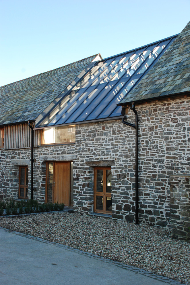 Inspiration for an expansive and gey rustic two floor front detached house in Cornwall with stone cladding, a half-hip roof and a grey roof.