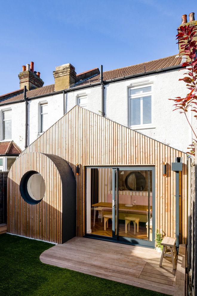 Photo of a small traditional bungalow terraced house in London with wood cladding, a pitched roof and a green roof.