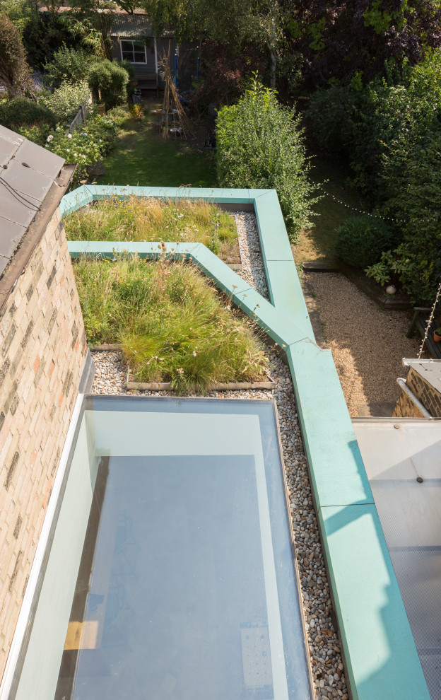 Modern inredning av ett mellanstort grönt radhus, med tre eller fler plan, metallfasad, platt tak och levande tak
