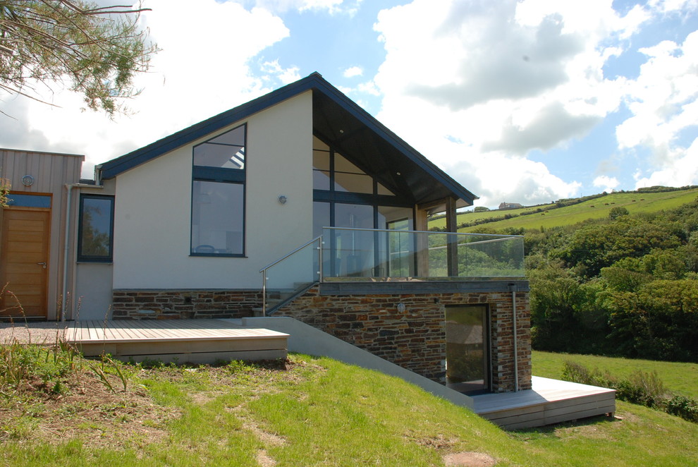 Photo of a medium sized and white contemporary two floor side detached house in Cornwall with stone cladding, a pitched roof, a tiled roof and a grey roof.