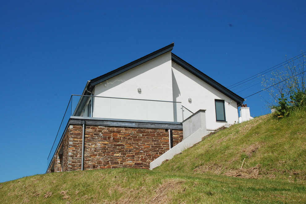 Cette image montre une façade de maison blanche design en pierre de taille moyenne et à un étage avec un toit à deux pans, un toit en tuile et un toit gris.
