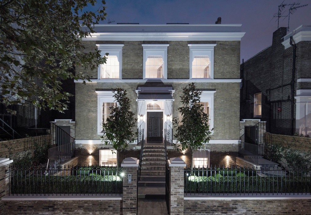Inspiration for a large and yellow traditional brick house exterior in London with three floors and a flat roof.