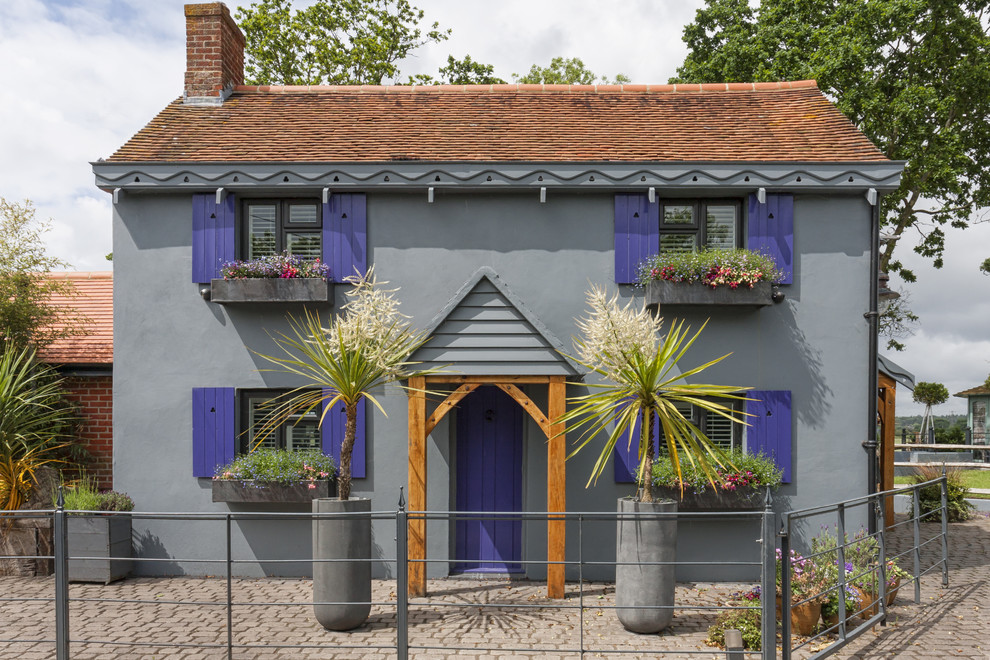 Ejemplo de fachada de casa gris clásica renovada de dos plantas con tejado a dos aguas y tejado de teja de barro