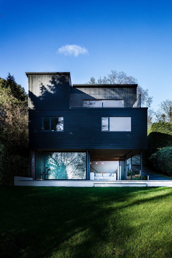 This is an example of a black contemporary house exterior in Hampshire with wood cladding.