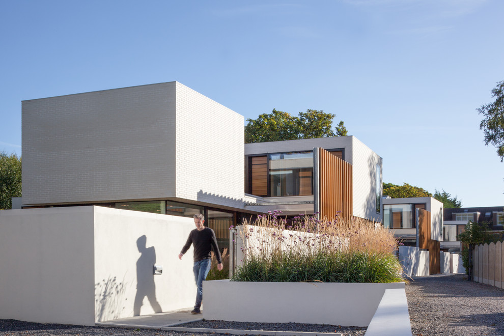 Cette photo montre une façade de maison blanche moderne en brique de taille moyenne et de plain-pied avec un toit plat.