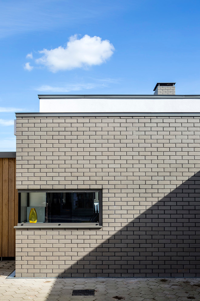 Idee per la facciata di una casa grigia contemporanea a tre piani di medie dimensioni con rivestimento in mattoni