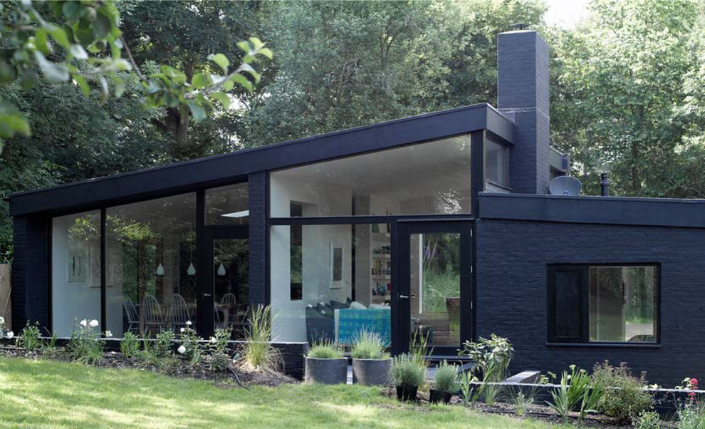 Ejemplo de fachada negra actual de tamaño medio de una planta con revestimiento de ladrillo y tejado a dos aguas