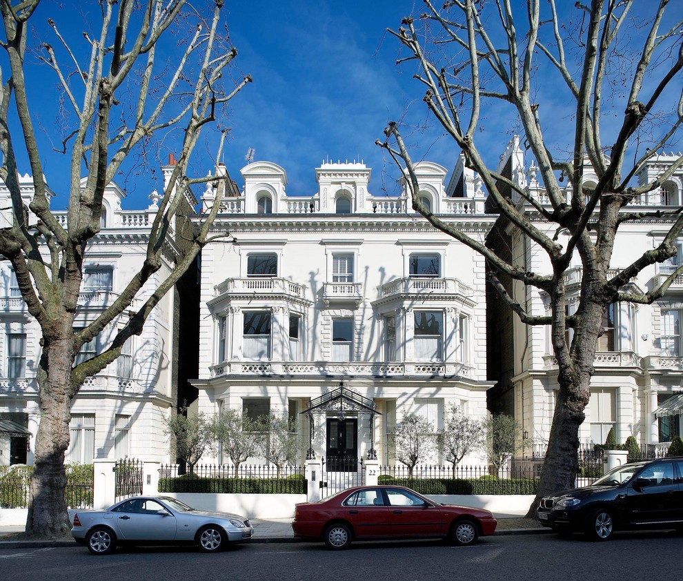 Imagen de fachada blanca clásica grande de tres plantas con revestimiento de estuco y tejado a doble faldón