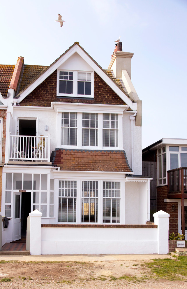 Esempio della facciata di una casa bifamiliare grande bianca stile marinaro a tre piani con rivestimento in stucco, tetto a capanna, copertura in tegole e tetto marrone