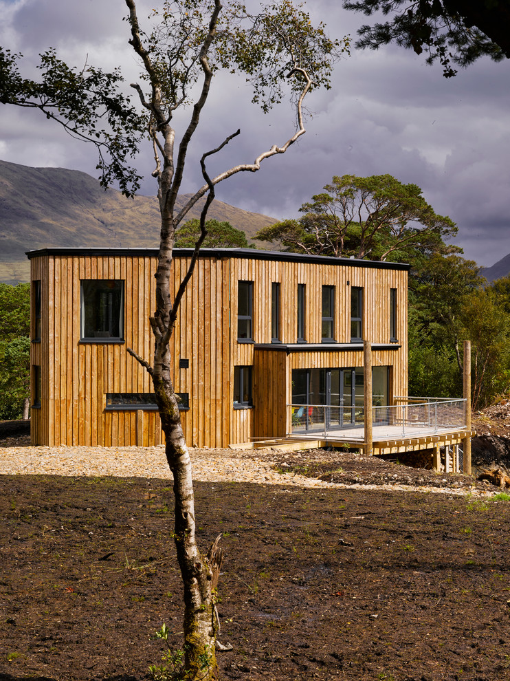 This is an example of a large contemporary two floor house exterior in Other with wood cladding and a flat roof.