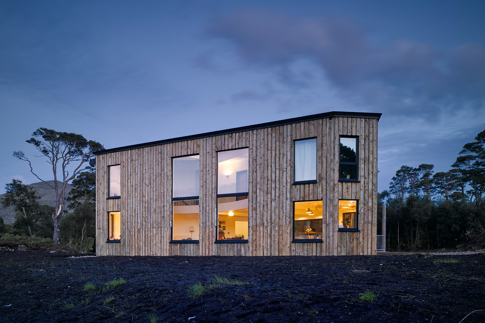 Photo of a large contemporary house exterior in Other with wood cladding and a flat roof.