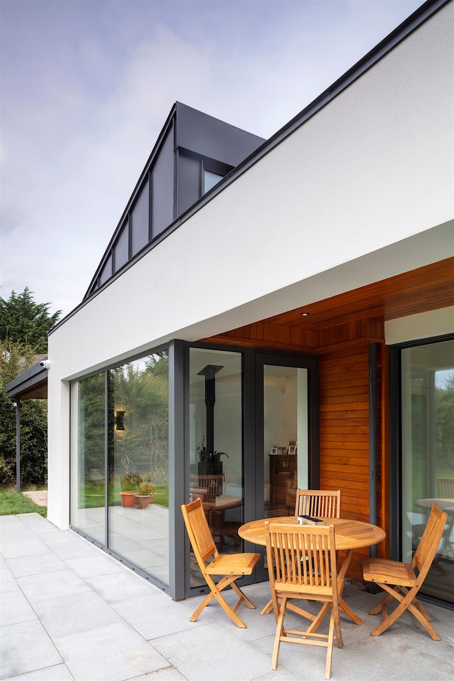 Идея дизайна: большой, двухэтажный, серый частный загородный дом в стиле модернизм с облицовкой из цементной штукатурки, двускатной крышей и черепичной крышей