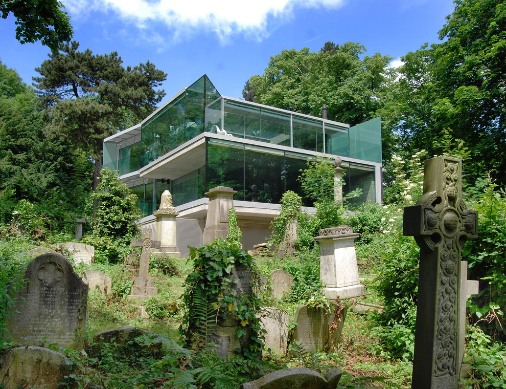 Foto på ett stort funkis grått hus, med tre eller fler plan och glasfasad