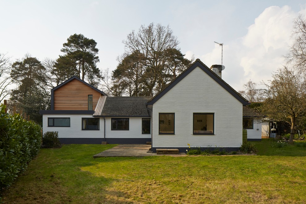 Aménagement d'une façade de maison blanche contemporaine à un étage avec un revêtement mixte et un toit à deux pans.