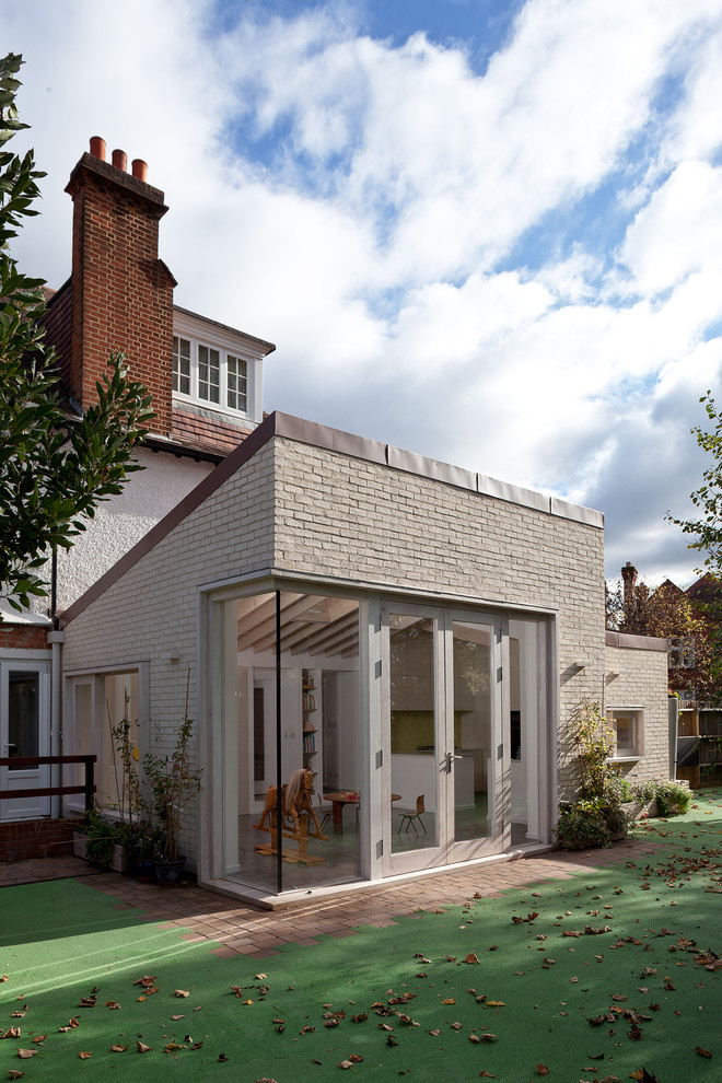 Large danish white one-story brick exterior home photo in Surrey with a metal roof