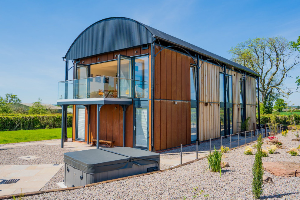 Стильный дизайн: большой, двухэтажный, оранжевый частный загородный дом в стиле модернизм с облицовкой из металла и металлической крышей - последний тренд