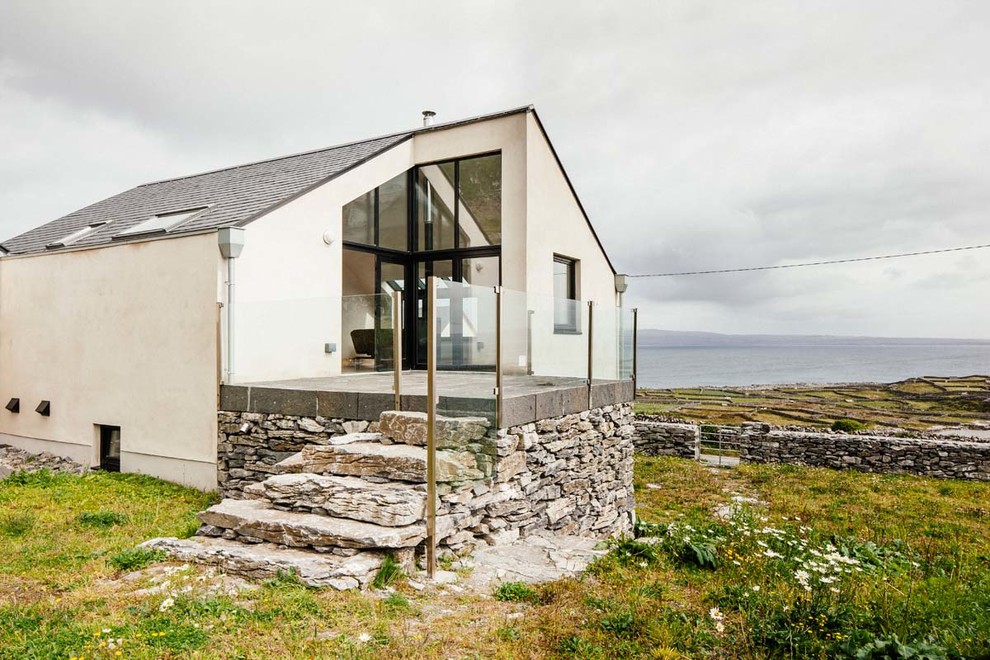 Источник вдохновения для домашнего уюта: белый частный загородный дом в морском стиле с облицовкой из бетона и двускатной крышей