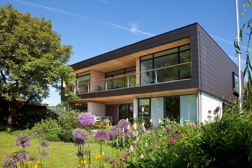 This is an example of a large and black scandi two floor house exterior in Aarhus with mixed cladding and a flat roof.