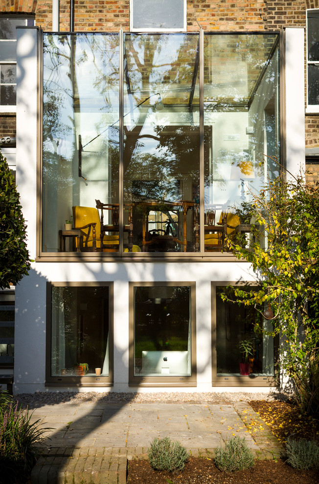 Cette image montre une façade de maison blanche design en verre de taille moyenne et à un étage.
