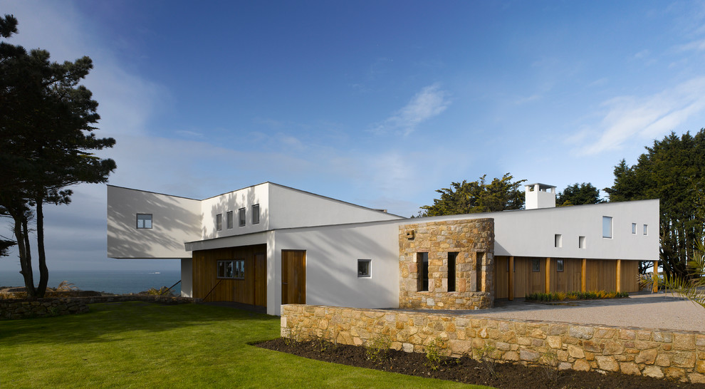 Cette image montre une façade de maison blanche design à niveaux décalés avec un revêtement mixte.