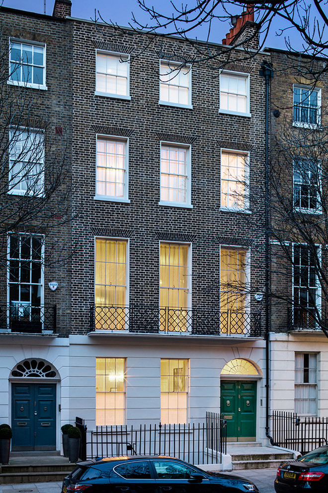 This is an example of an expansive and white traditional brick house exterior in London with three floors and a mansard roof.