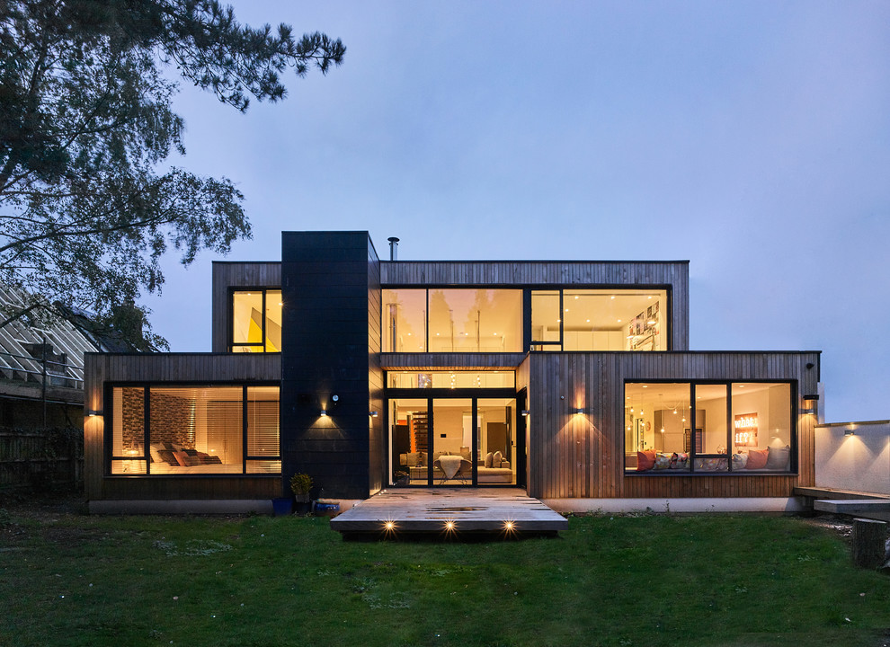 Idée de décoration pour une façade de maison design en bois de taille moyenne et à un étage avec un toit plat.