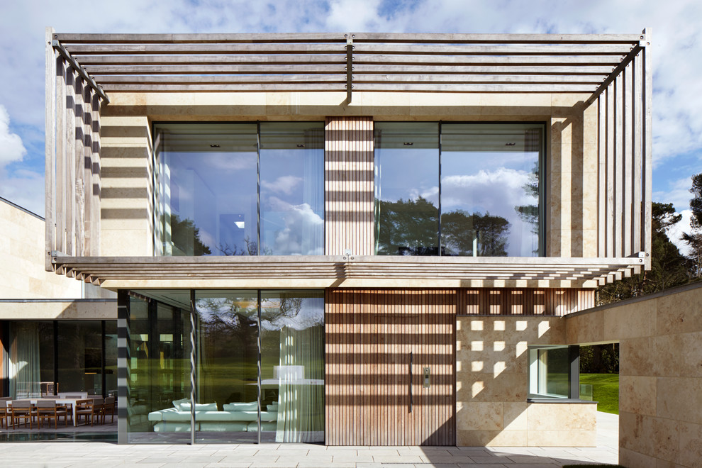 Modelo de fachada de casa beige contemporánea de dos plantas con tejado plano y revestimientos combinados