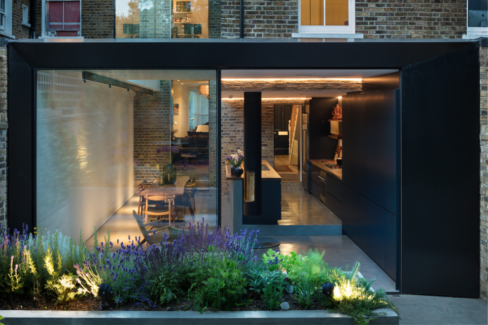 Large and black contemporary terraced house in London with four floors, metal cladding and a pitched roof.