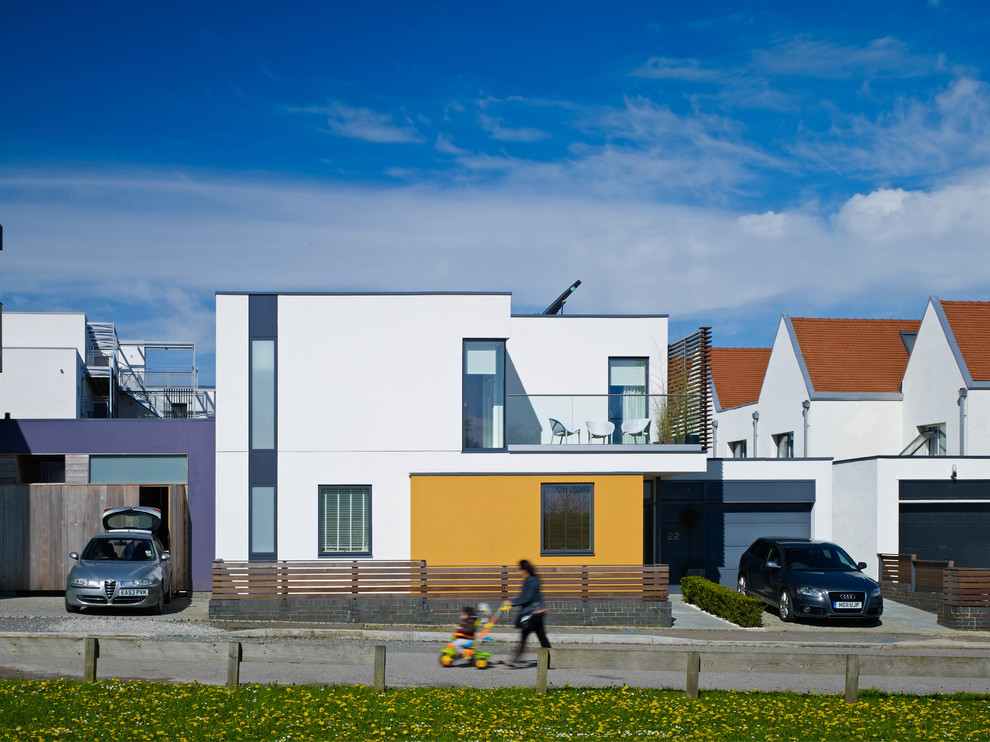 This is an example of a white and medium sized contemporary two floor render house exterior in London with a flat roof.