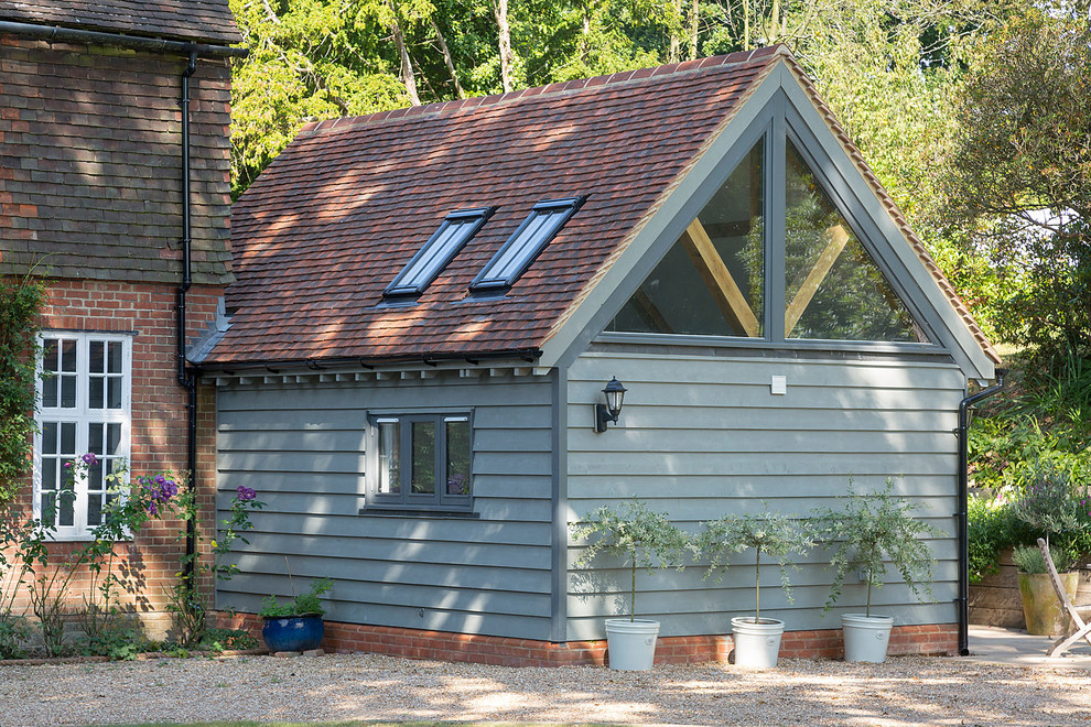 Imagen de fachada de casa campestre con revestimiento de madera, tejado a dos aguas y tejado de teja de barro