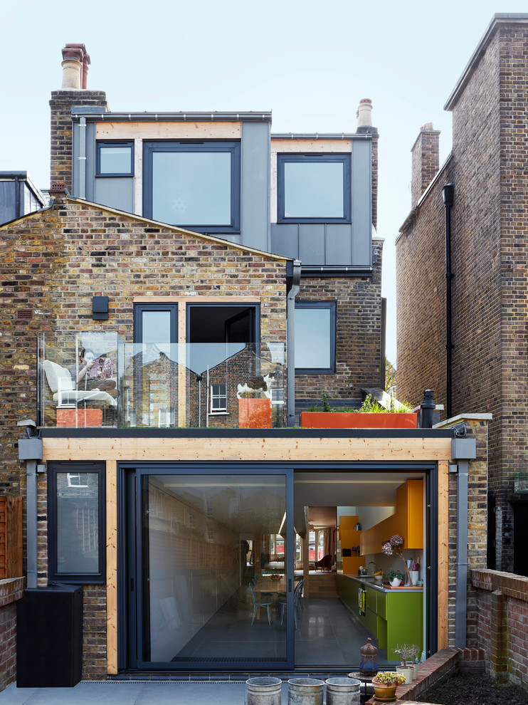 This is an example of a large contemporary rear extension in London with three floors and mixed cladding.