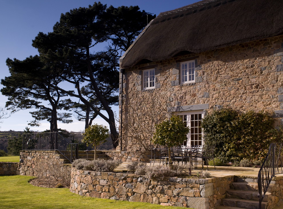 Photo of a farmhouse two floor house exterior in Channel Islands with stone cladding.