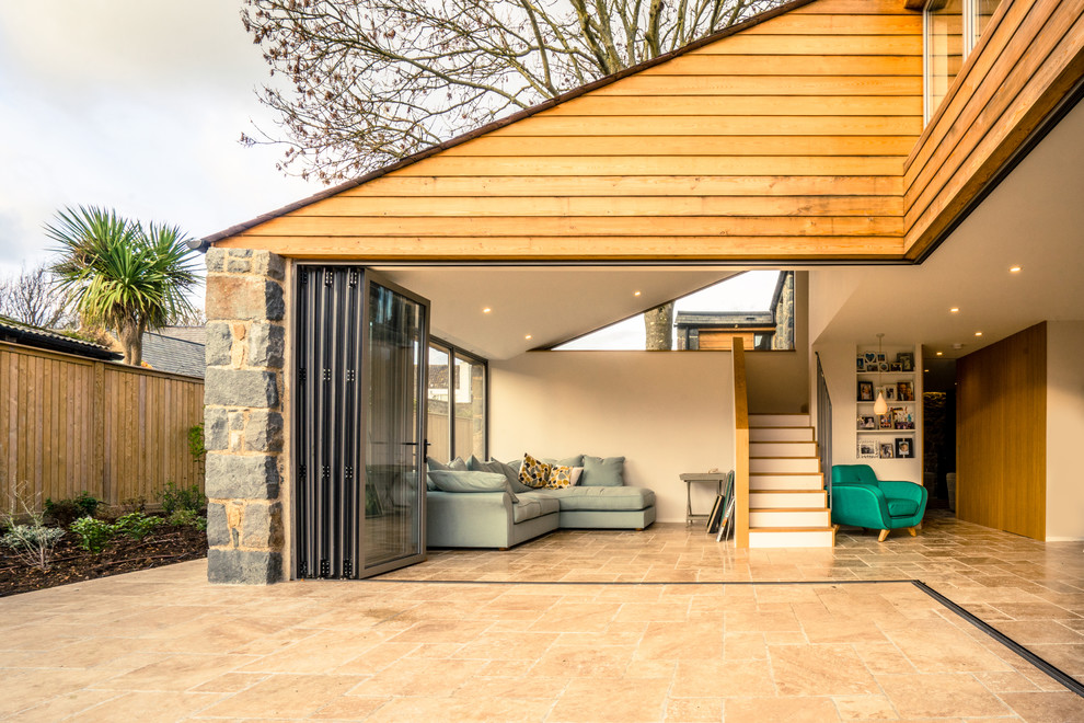 Photo of a beige rustic two floor house exterior in Channel Islands with wood cladding.