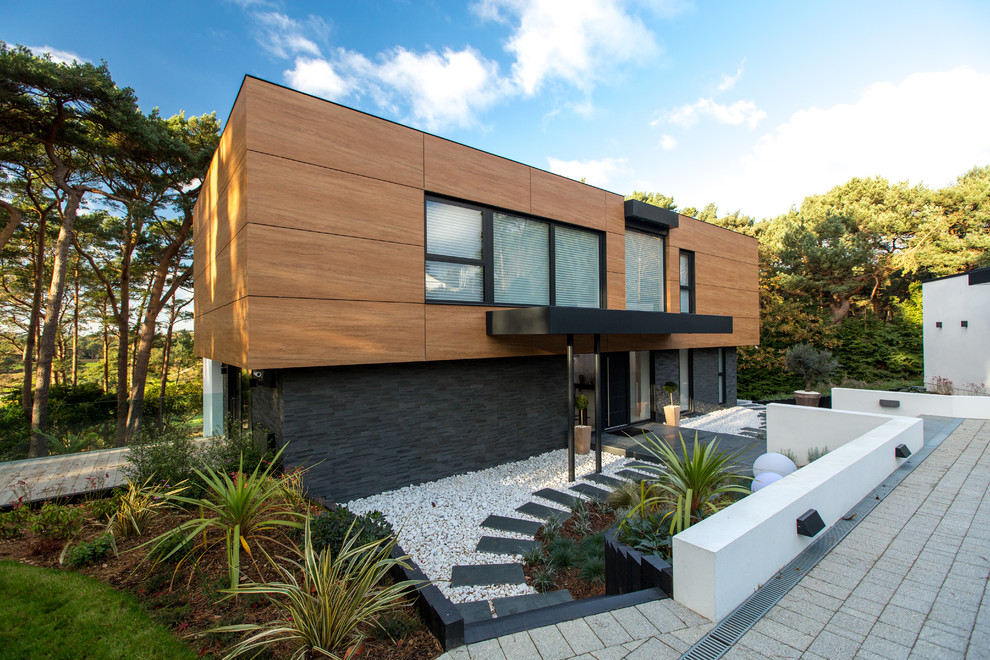 Aménagement d'une façade de maison noire contemporaine en bois de taille moyenne et à un étage avec un toit plat.