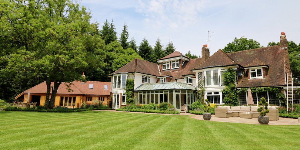 This is an example of a large rural house exterior in London with three floors, mixed cladding and a pitched roof.