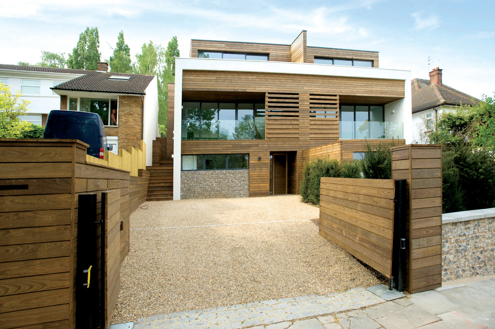 Brown contemporary house exterior in London with three floors, wood cladding and a flat roof.