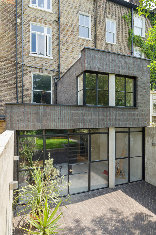 Mittelgroßes, Zweistöckiges Industrial Reihenhaus mit Backsteinfassade, grauer Fassadenfarbe, Flachdach und Misch-Dachdeckung in London