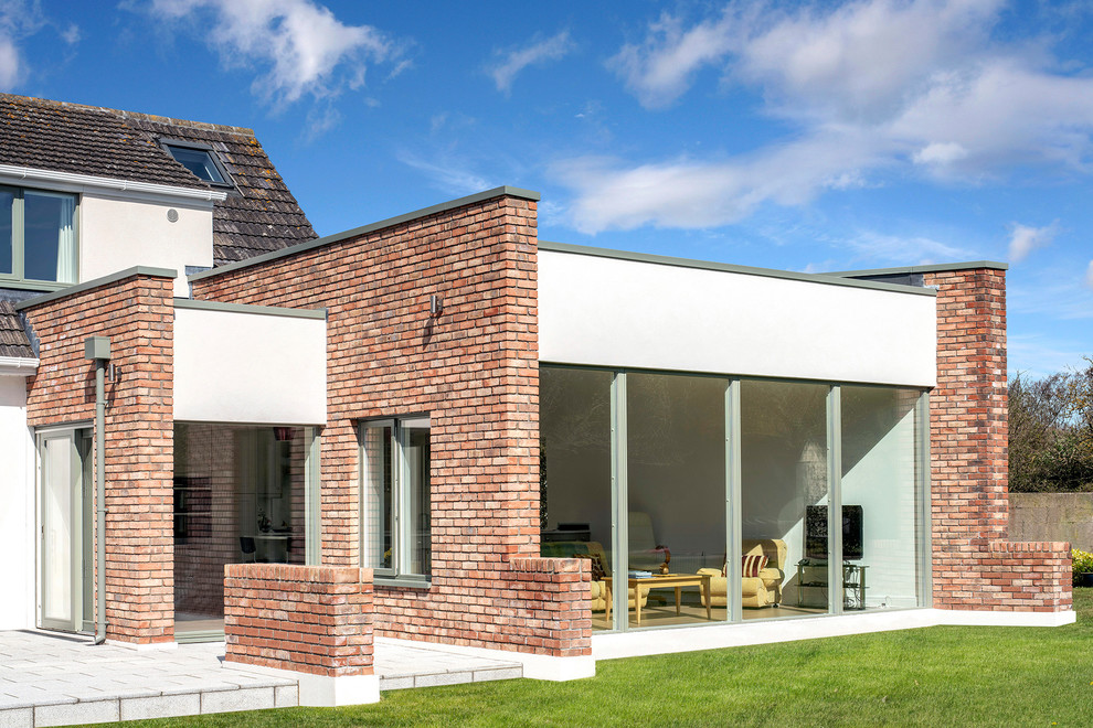 Aménagement d'une grande façade de maison marron contemporaine en brique à un étage avec un toit plat.