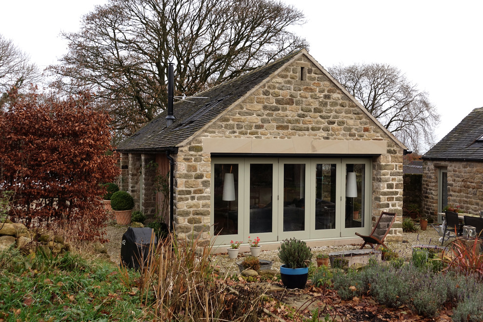 Imagen de fachada de casa campestre pequeña de una planta con revestimiento de piedra, tejado a dos aguas y tejado de teja de barro