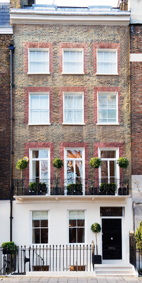 Large and brown classic brick terraced house in London with three floors, a pitched roof and a tiled roof.