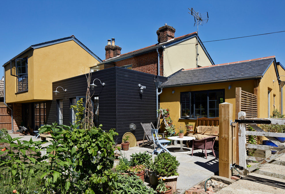 Modelo de fachada de casa amarilla de estilo de casa de campo de tamaño medio de dos plantas con revestimiento de madera, tejado a dos aguas y tejado de varios materiales