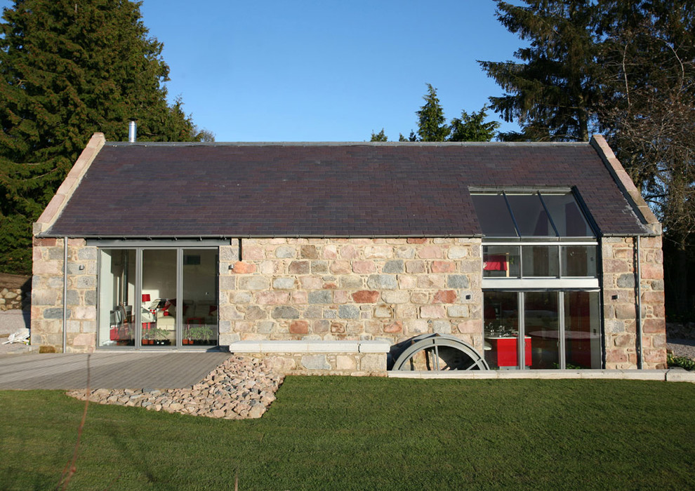 Imagen de fachada contemporánea de tamaño medio de dos plantas con revestimiento de piedra y tejado a dos aguas