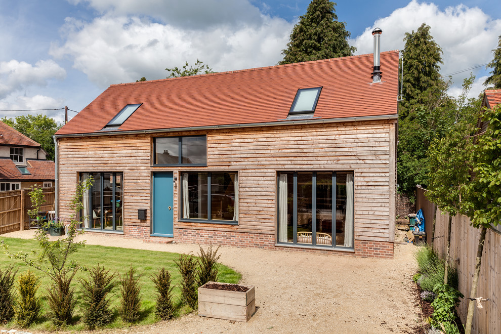 Inspiration for a medium sized and beige scandinavian two floor detached house in Buckinghamshire with wood cladding, a pitched roof and a tiled roof.