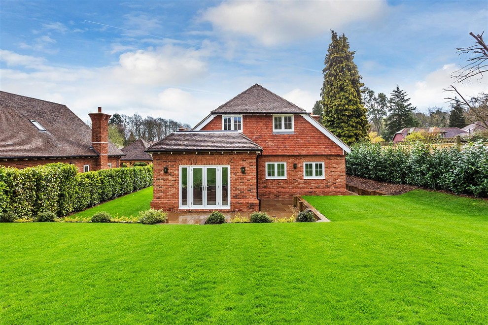 Photo of a red and large classic two floor brick detached house in Surrey with a pitched roof.