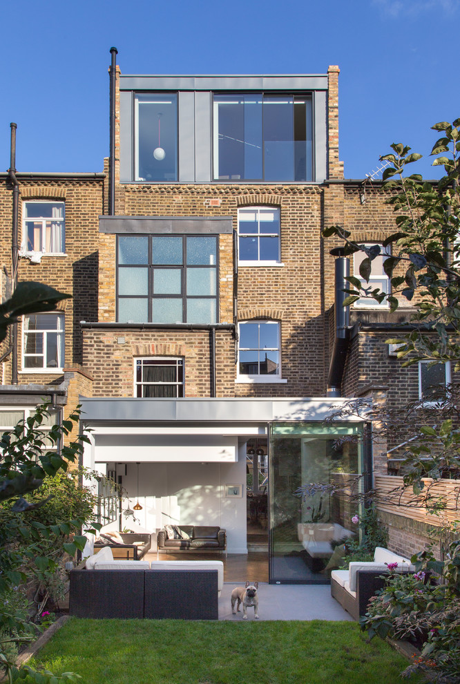 Large and beige contemporary brick and rear house exterior in London with three floors, a pitched roof and a tiled roof.