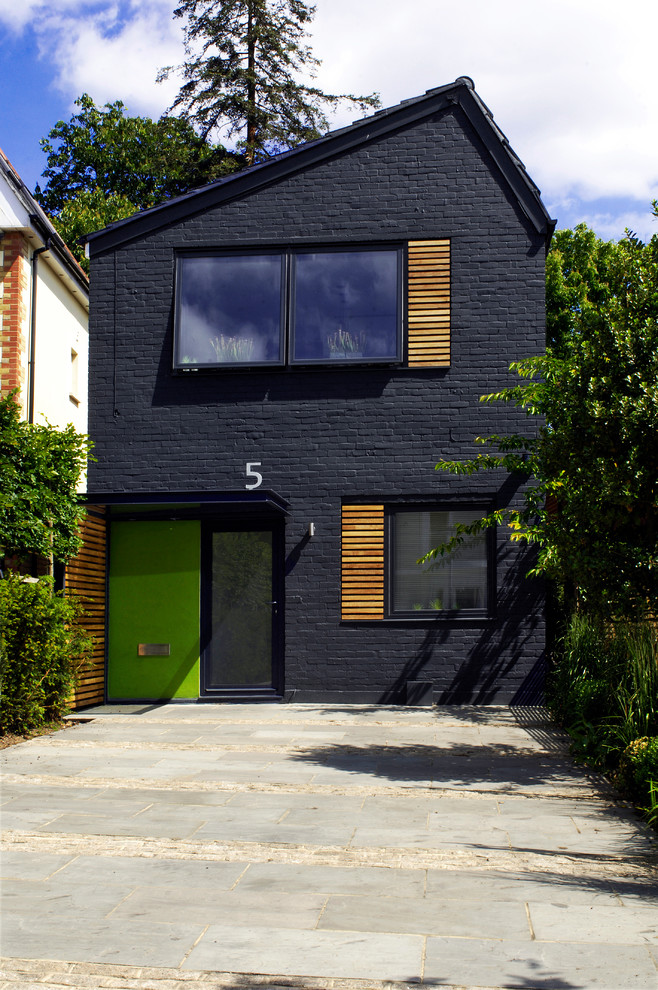 На фото: двухэтажный, кирпичный, черный дом среднего размера в современном стиле с двускатной крышей и черепичной крышей